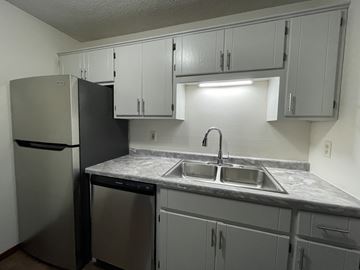 Sauk Rapids apartment for rent - A kitchen with a black refrigerator and a marble counter top.