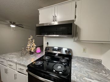 Sauk Rapids apartment for rent - A black stove top oven in a kitchen with a pink light on.