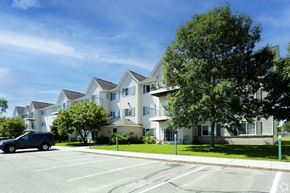 Isanti apartment for rent - A large white building with a blue car parked in front.