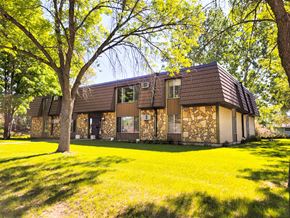 Little Falls apartment for rent - A house with a brown roof and a stone wall is surrounded by trees.
