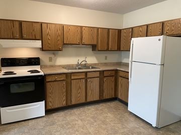 Little Falls apartment for rent - A kitchen with wooden cabinets and a white refrigerator.