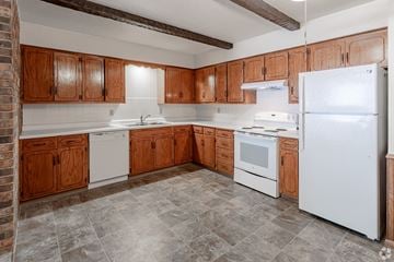 Sartell apartment for rent - A kitchen with wooden cabinets and white appliances.