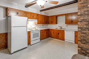 Sartell apartment for rent - A kitchen with a white refrigerator, wooden cabinets, and a brick wall.
