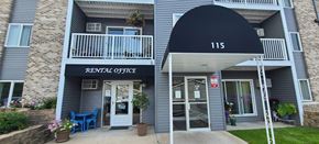 Sauk Rapids apartment for rent - the front of a grey apartment building with a blue awning and a door