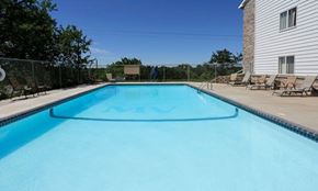 Sauk Rapids apartment for rent - A rectangular blue swimming pool with a white fence and a house in the background.
