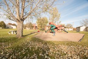 Little Falls townhouse for rent - A playground with a green slide and a red building in the background.