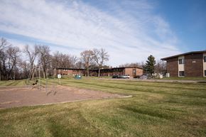 Milaca apartment for rent - A playground with a swing set and a building in the background.