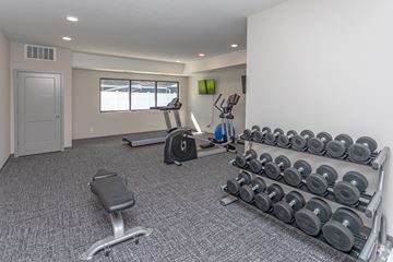 Owatonna apartment for rent - A home gym with a bench, weights, and exercise equipment.