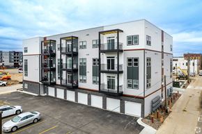 Owatonna apartment for rent - A modern apartment building with a parking lot in front.