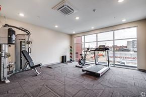 Owatonna apartment for rent - A gym with a treadmill, weights, and exercise equipment.