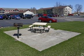 Albertville apartment for rent - A picnic table sits in a concrete area in front of a parking lot.