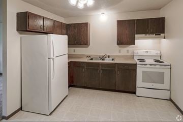 St Cloud apartment for rent - A white refrigerator is in a kitchen with brown cabinets.