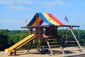 Sauk Rapids apartment for rent - A playground with a yellow slide and a wooden structure with flags.