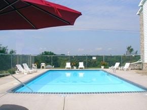 Sauk Rapids apartment for rent - A red umbrella is shading a pool area with chairs.