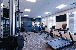 Cambridge apartment for rent - a gym with various exercise machines and a tv