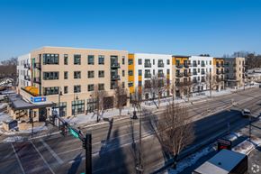 Monona apartment for rent - A modern building with yellow and white exterior is surrounded by a snowy landscape.