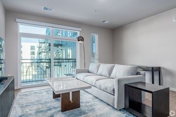 Monona apartment for rent - A modern living room with a grey sofa and a glass table.