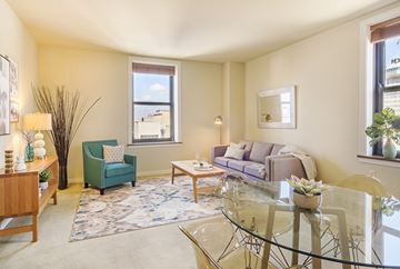 Milwaukee apartment for rent - A living room with a glass table and a green armchair.