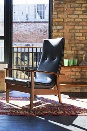 Milwaukee apartment for rent - A black leather chair with wooden legs sits in front of a window.