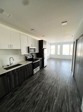 Milwaukee apartment for rent - A kitchen with dark wood floors and white cabinets.