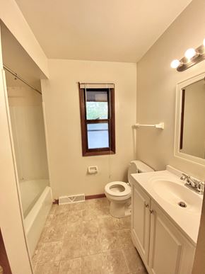 Greendale townhouse for rent - A bathroom with a toilet, sink, and a window at Root River Apartments, Greendale, 53129