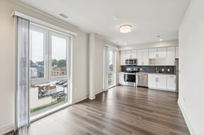 Washington apartment for rent - A modern kitchen with white cabinets and a wooden floor.