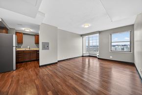 Cleveland apartment for rent - A spacious room with wooden flooring and a large window overlooking a cityscape.