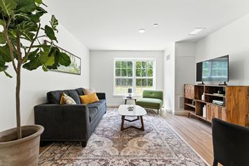 Stow apartment for rent - A living room with a grey couch and a green chair.