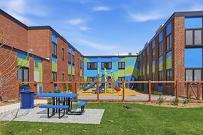 Northampton apartment for rent - A playground area with a slide and picnic tables is surrounded by colorful buildings.