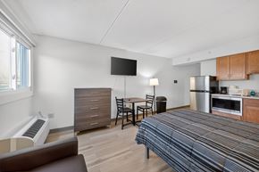 Dorchester apartment for rent - A bedroom with a bed, a couch, a chair, a table, a microwave, and a refrigerator.