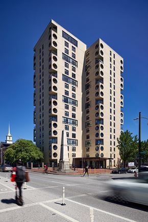 Baltimore apartment for rent - A tall building with circular windows is located on a street corner.