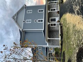 Amherst apartment for rent - A house with a grey roof and white windows is surrounded by a grassy area.