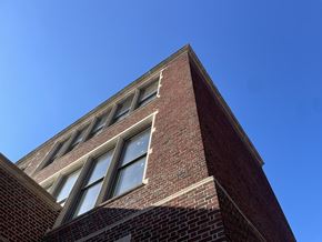 Pittsburgh apartment for rent - the top of a brick building with windows against a blue sky