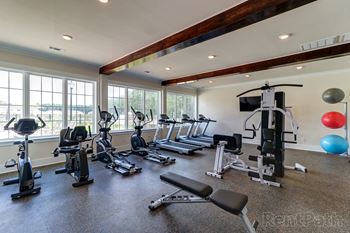 Gym with cardio equipment and windows with a lake view