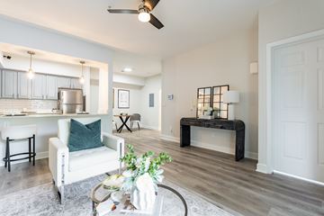 Goose Creek apartment for rent - A living room with a white chair and a table with a plant on it.