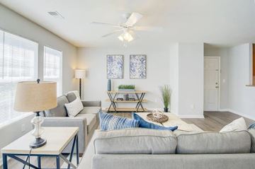 Charleston apartment for rent - A living room with a grey couch, a table with a lamp, and a ceiling fan.