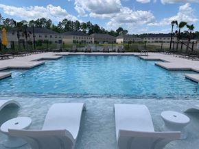 Bloomingdale apartment for rent - A swimming pool with white lounge chairs and a yellow umbrella.