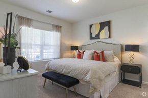 Bloomingdale apartment for rent - A bedroom with a white bed and a black stool.