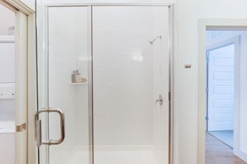 A shower with a glass door in a white bathroom