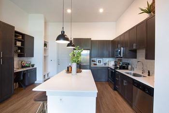 A large kitchen with a white island and dark cabinets