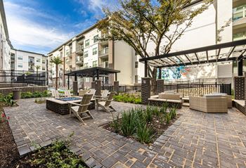 An outdoor patio with tables and chairs and a building in the background