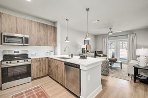Kennesaw apartment for rent - A modern kitchen with wooden cabinets and stainless steel appliances at The Ashton at East Park Apartments, Georgia, 30144