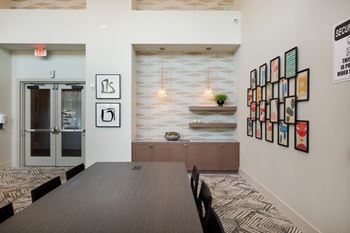 A conference room with a wooden table and chairs and a wall filled with framed art