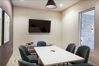 A conference room with a table and chairs and a tv on the wall