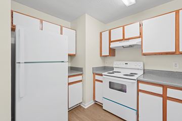 Durham apartment for rent - A white refrigerator is in a kitchen with wooden cabinets.