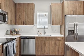 Crestview apartment for rent - A modern kitchen with wooden cabinets and stainless steel appliances.at The Exchange at Crestview Apartments, Crestview, FL