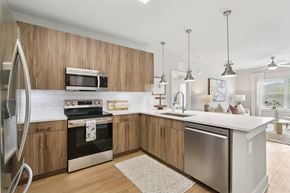 Kennesaw apartment for rent - A modern kitchen with wooden cabinets and stainless steel appliances.at The Delaney at East Park Apartments, Kennesaw, Georgia
