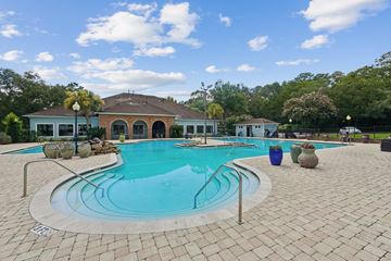 Tallahassee apartment for rent - A swimming pool surrounded by a brick patio and a house in the background.
