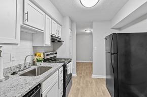 Marietta apartment for rent - A black refrigerator is on the right in a kitchen with white cabinets.at Magnolia at Whitlock, Marietta, GA 30064