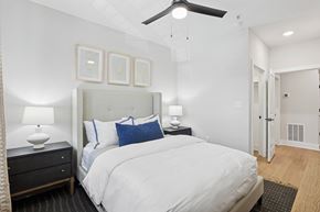 Atlanta apartment for rent - A bedroom with a large bed, a ceiling fan, and a nightstand with a lamp at Union Eleven Apartments, Atlanta, 30324
